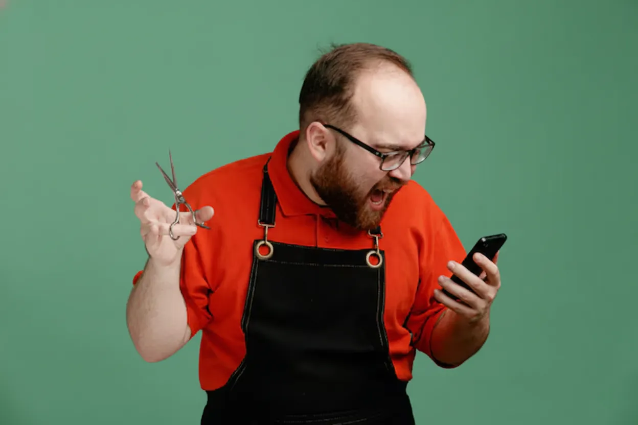 Barbeiro atendendo cliente enquanto olha mensagens no celular
